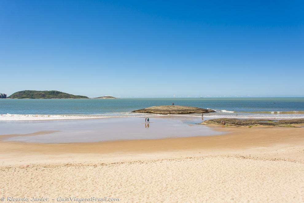 Imagem de turistas nas pedras admirando o lindo mar da Praia do Morro